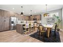 Open kitchen and dining area with stainless appliances, island seating, and modern light fixtures at 4127 Tejon St, Denver, CO 80211