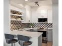 Updated kitchen features stainless appliances, grey and white cabinets, quartz countertops, and decorative backsplash at 345 Fillmore # 407, Denver, CO 80206