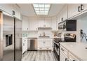 Bright kitchen featuring white cabinets, stainless steel appliances, and a skylight at 6140 Depew St, Arvada, CO 80003