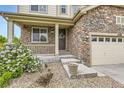 Inviting front porch with stone accents, decorative plants, and well-maintained landscaping at 6108 S Harvest Ct, Aurora, CO 80016
