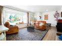 Bright living room with large bay window, wood floors, area rug and comfortable leather furniture at 8276 E Easter Pl, Centennial, CO 80112