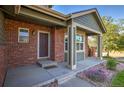 Inviting front porch with brick columns, a covered entrance, and vibrant landscaping, offering curb appeal at 2587 S Flanders Ct, Aurora, CO 80013