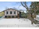 Ranch style home with a fenced yard, snow covered lawn, and mature trees at 15895 E 17Th Pl, Aurora, CO 80011