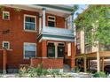 Inviting brick townhouse showcasing a cozy front porch with classic columns and a landscaped garden at 1243 N Lafayette St, Denver, CO 80218