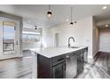 Bright kitchen features a center island with a sink, stainless steel appliances, and wood flooring at 1208 Quitman St # 202, Denver, CO 80204