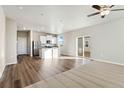 Bright, open-concept living room featuring hardwood floors, ceiling fan and sliding glass doors at 3003 Pershing St, Strasburg, CO 80136