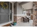 Inviting front porch with stone accents, neutral furniture and a decorative wreath on the front door at 10570 Sundial Rim Rd, Highlands Ranch, CO 80126