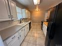 Functional kitchen featuring white cabinets, tiled floors, and modern black appliances at 1836 E Mineral Ave, Centennial, CO 80122