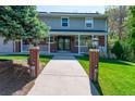 Inviting front of a two-story home featuring a brick walkway, porch, and well-maintained lawn at 6150 Reed St, Arvada, CO 80003