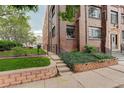 Brick apartment building exterior with garden beds and secure wrought-iron fencing at 1060 N Washington St # 1A, Denver, CO 80203