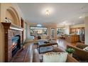 Inviting living room with a cozy fireplace, open floor plan, hardwood floors, and a view into the kitchen and dining area at 10900 Parker Vista Rd, Parker, CO 80138