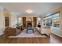 Elegant living room featuring a fireplace, built-in bookshelves, hardwood floors, and abundant natural light from large windows at 10900 Parker Vista Rd, Parker, CO 80138