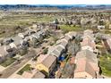 An aerial view showcases homes in a suburban neighborhood with views of open land and mountains at 6853 W Rockland Pl, Littleton, CO 80128