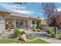 Charming front of home featuring a manicured yard, decorative landscaping, and large windows at 10985 Ambush Rock, Littleton, CO 80125