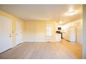 An open living area with light hardwood floors flowing into an adjacent white kitchen at 919 S Dawson Way # 7, Aurora, CO 80012