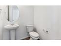 Clean powder room featuring a pedestal sink, round mirror, and modern fixtures at 4511 Boone Cir, Brighton, CO 80601
