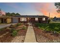 Charming brick home featuring a beautifully landscaped front yard at sunset at 5593 E Center Ave, Denver, CO 80246