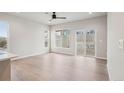 Bright living room featuring light wood floors, modern ceiling fan, and large windows overlooking the backyard at 17673 Brass Buckle Way, Monument, CO 80132