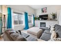 Bright living room features a cozy fireplace, a large gray couch and bright accents at 6774 St Vrain Ranch Blvd, Firestone, CO 80504