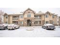 The front of the building with parking area features stone accents and multiple balconies in the winter at 10487 W Hampden Ave # 101, Lakewood, CO 80227