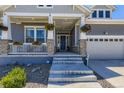 View of charming covered porch with stone and wood columns, hanging flower baskets, and a blue front door at 3344 Carabiner St, Castle Rock, CO 80108