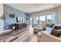 Open-concept living room boasts a modern accent wall, hardwood floors, large windows, and stylish decor at 3344 Carabiner St, Castle Rock, CO 80108