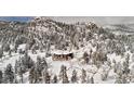 Aerial view of a log home nestled in a snow-covered mountain forest, offering privacy at 3999 Evans Ranch Rd, Evergreen, CO 80439