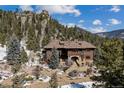 A grand log home with stone accents, a multi-tiered entrance, and mature evergreens graces this mountain property at 3999 Evans Ranch Rd, Evergreen, CO 80439