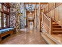 Grand foyer with stone walls, log beams, high ceilings, and staircase at 3999 Evans Ranch Rd, Evergreen, CO 80439