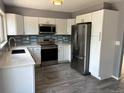 Updated kitchen featuring white cabinets, stainless steel appliances, and a stylish backsplash at 3613 S Olathe St, Aurora, CO 80013