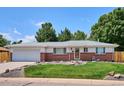 Charming single-story home with a well-manicured lawn, brick accents, and mature trees at 1687 S Field Ct, Lakewood, CO 80232