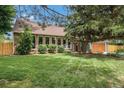 Lovely brick home with a lush green lawn, mature shade trees, and an attached garage; a welcoming and picturesque scene at 14887 W 49Th Pl, Golden, CO 80403