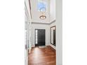 Bright foyer with hardwood floors, a grand light fixture, and a black front door at 6475 S Newcastle Way, Aurora, CO 80016