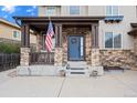 Inviting front porch with stone columns, American flag, and a blue front door with wreath detail at 6475 S Newcastle Way, Aurora, CO 80016