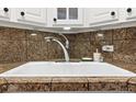 Close-up of a clean kitchen sink with a chrome faucet and neutral granite backsplash at 1390 N Emerson St # 406, Denver, CO 80218