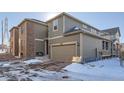 Rear view of two-story home with attached garage and snow-covered ground at 9308 Inca Dove Cir, Littleton, CO 80125