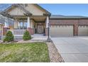 Close-up of charming home with brick accents, well-kept lawn, and a three-car garage at 1978 Granger Cir, Castle Rock, CO 80109