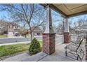 Inviting front porch with brick columns, white railings, and seating overlooking the street at 1978 Granger Cir, Castle Rock, CO 80109
