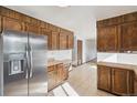 Spacious kitchen with wood cabinets, stainless steel refrigerator, and tile flooring at 4522 S Robb St, Littleton, CO 80127