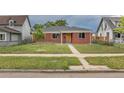 Single story brick home featuring a simple and tidy lawn with a small tree at 4453 Fillmore St, Denver, CO 80216