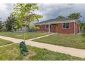 View of brick home, sidewalk, and young tree in yard with cloudy skies overhead at 4453 Fillmore St, Denver, CO 80216