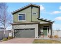 Charming two-story home featuring a green facade, gray garage door, and well-maintained front yard at 19055 E 55Th Ave, Denver, CO 80249