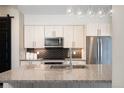 Modern kitchen island with granite countertop, a sink, and stainless steel appliances at 3198 Blake St # 502, Denver, CO 80205