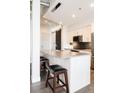 Modern kitchen island with a granite countertop, stools, and elegant lighting at 3198 Blake St # 502, Denver, CO 80205