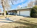 View of the white brick exterior of the house with an attached two car garage and concrete driveway at 1630 S Valentine Way, Lakewood, CO 80228