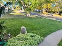 A lovely green lawn with a large rock and landscaping sits adjacent to a sidewalk at 2789 S Ivan Way, Denver, CO 80227