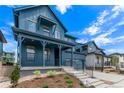 Blue two-story home featuring a covered porch, tasteful landscaping, and a two-car garage at 5608 Grandville Ave, Longmont, CO 80503