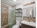 Well-lit bathroom featuring a sleek vanity, patterned tile shower, and modern fixtures at 5873 S Prince St # 209B, Littleton, CO 80120