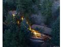 Aerial view of a pair of illuminated homes nestled among dense trees at 9506 S Deer Creek Canyon Rd, Littleton, CO 80127