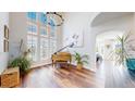 Sun-filled living room with tall ceilings, dark wood floors, large windows and a beautiful chandelier above a piano at 9804 N Crystal Lake Dr, Littleton, CO 80125